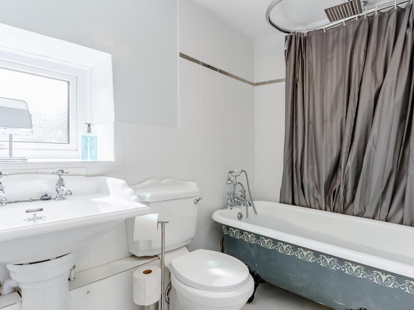 Et badeværelse med badekar, toilet og håndvask.