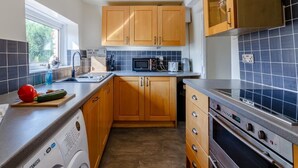 A compact kitchen with wooden cabinets, a built-in microwave, and a stainless steel oven. - 2 Bed in Kirkby Thore (oc-78744) (Kirkby Thore)