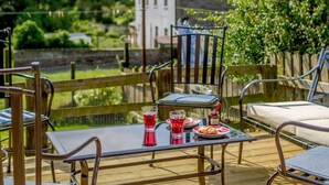 A deck with outdoor furniture, a table with a glass of red drink, and a view of a canal and greenery. - 2 Bed in Kirkby Thore (oc-78744) (Kirkby Thore)