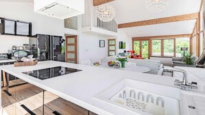 Una cocina moderna con una isla grande, un comedor con sofá y vistas a zonas verdes.