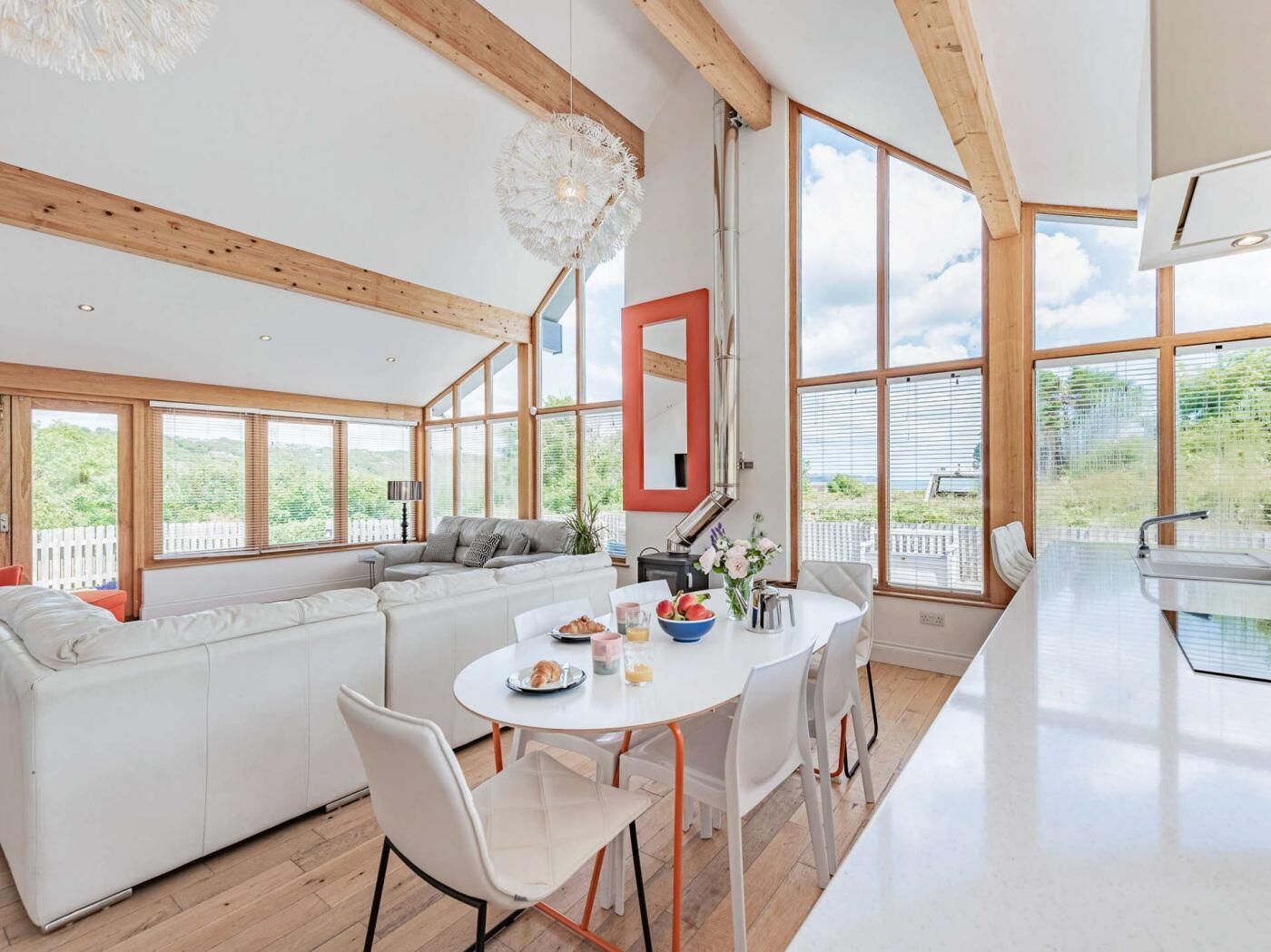 Une cuisine moderne avec un coin repas, de grandes fenêtres et une vue sur l’extérieur.