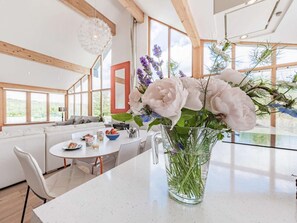 A modern kitchen with a dining area, large windows, and a vase of flowers on the counter. - 3 Bed in Pembroke (oc-66265) (Stackpole)