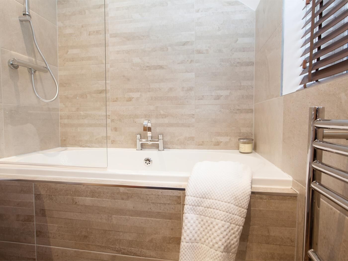Een moderne badkamer met een bad, douche en handdoekrek.