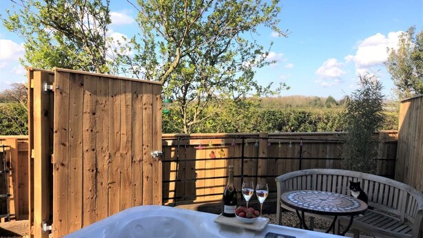 A hot tub with a wooden fence, a table with chairs, and a bottle of wine. - 2 Bed in Stokesley (oc-g0072) (Great Busby)