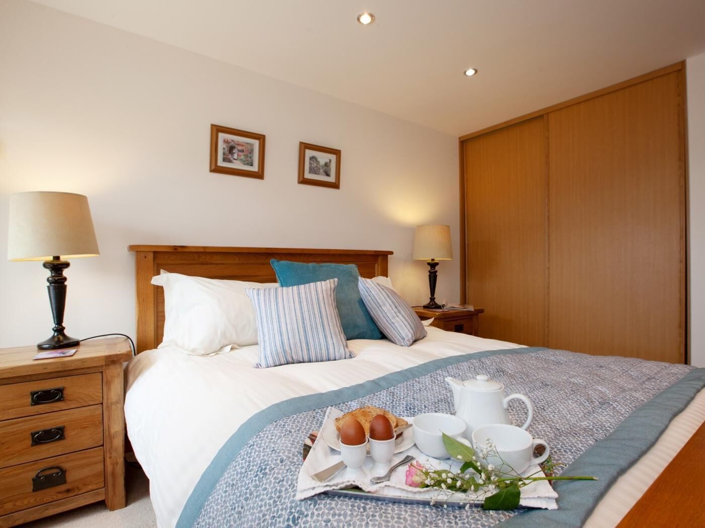 Un lit bien fait, avec des oreillers, une table de chevet avec une lampe et un plateau contenant des éléments pour le petit-déjeuner.