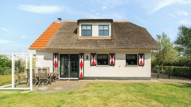 Ein einstöckiges Gebäude mit einem Strohdach, einem kleinen Oberlichtbalkon und einer Haustür mit Glasscheiben.