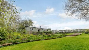 Een groene woning met houten omheining, gazon en heldere lucht.