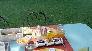 An outdoor dining table set with food and drinks, surrounded by a garden. - Guest Room in Family Home – The Engraving Room at the Foot of the Monts d'Ardèche (Jaujac)