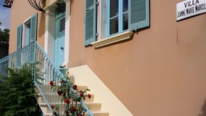 A building with a sign reading 'VILLA JEANNE MARIE MARCELLE,' a staircase with blue railings, and red flowers. - Guest Room in Family Home – The Engraving Room at the Foot of the Monts d'Ardèche (Jaujac)