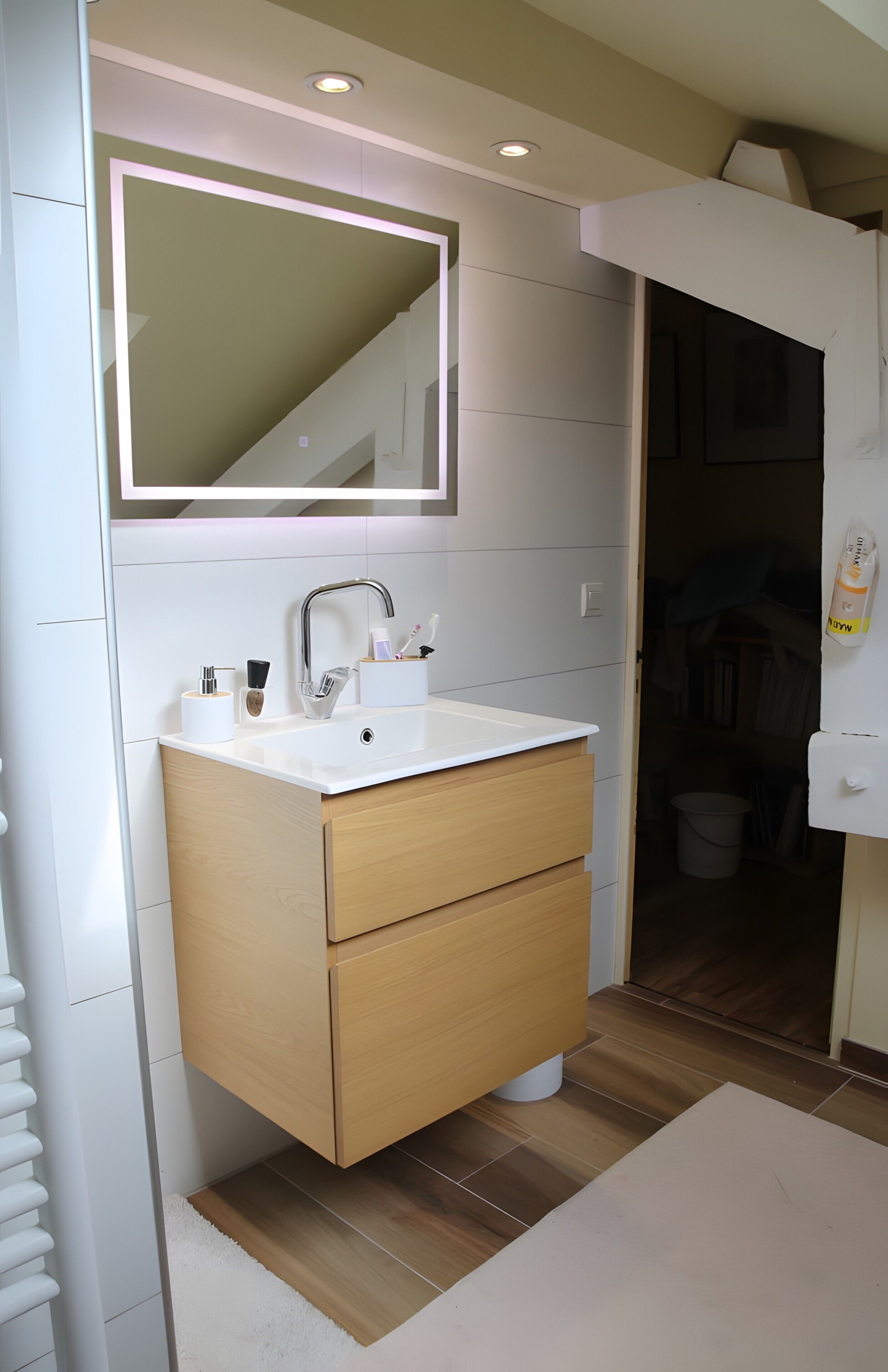 Une salle de bain moderne avec un lavabo blanc, un meuble-lavabo en bois et un grand miroir.