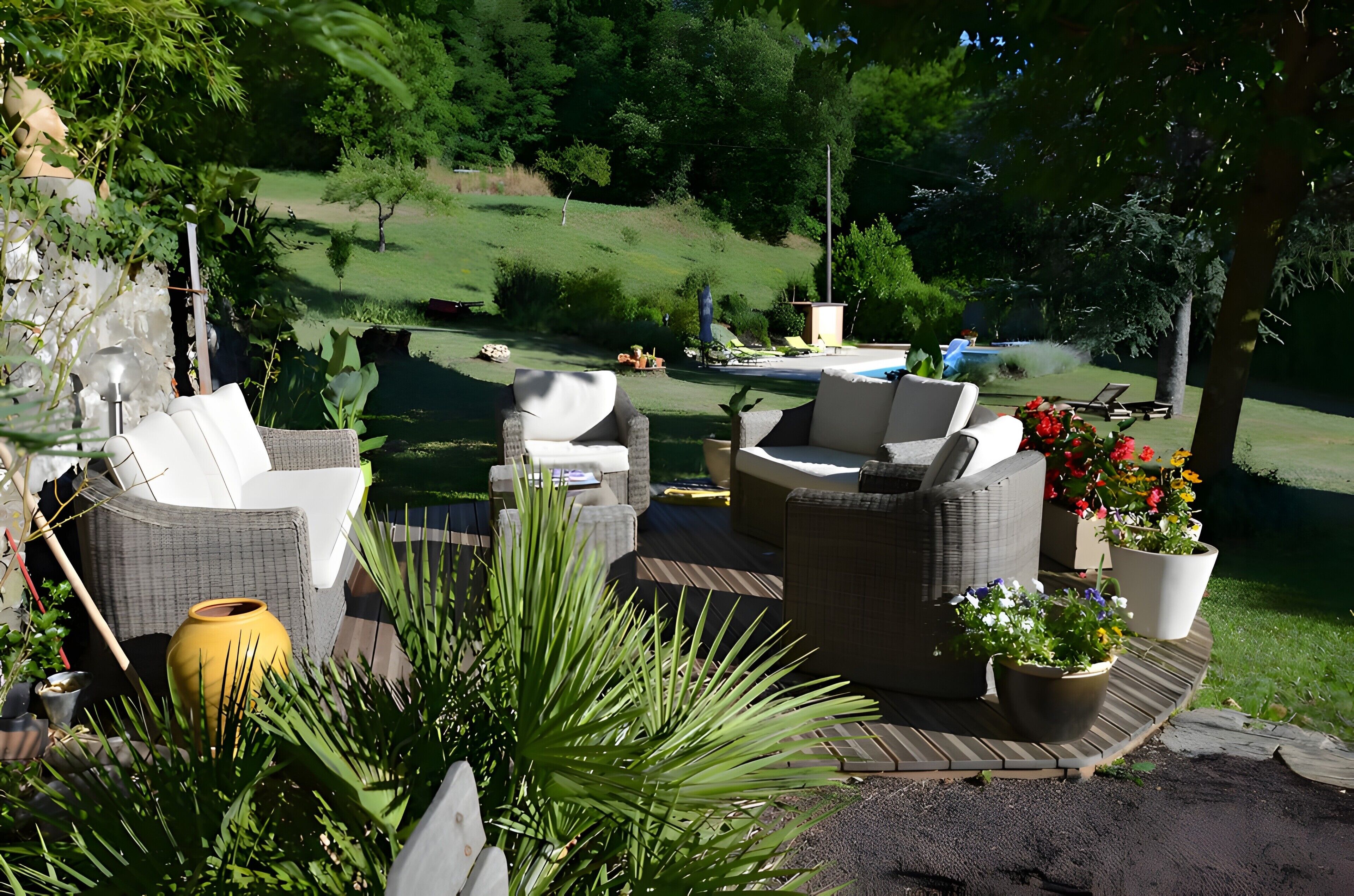 Une terrasse extérieure aménagée avec des meubles en osier, des plantes en pot et offrant une vue sur une pelouse et une piscine.