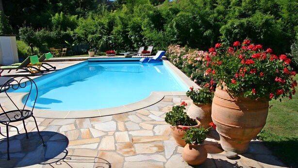 A swimming pool with a stone patio, lounge chairs, and potted plants. - Guest Room in Family Home – The Engraving Room at the Foot of the Monts d'Ardèche (Jaujac)