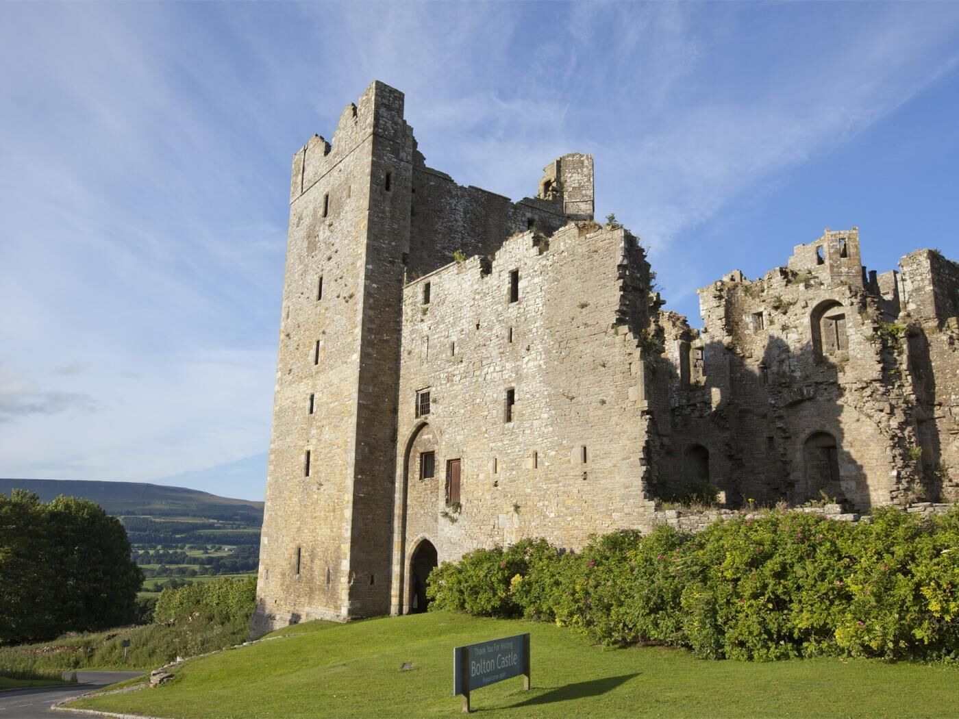 Eine historische Burg mit einem markanten Turm, Rundbogenfenstern und einem Schild, das sie als Touristenattraktion kennzeichnet.