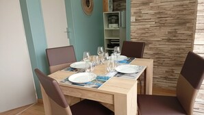 Un comedor con una mesa de madera dispuesta para cuatro personas, rodeada de sillas.