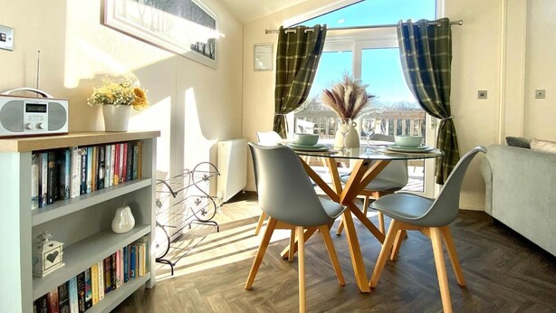 Un coin repas comprenant une table, des chaises, une bibliothèque et une fenêtre avec des rideaux.