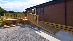 Une cabane en bois avec une terrasse, une petite fenêtre et une porte.