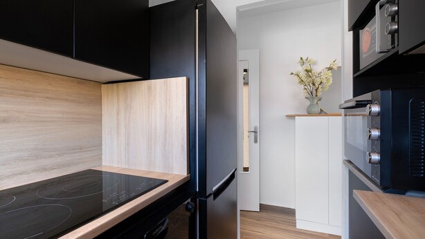 Una cocina moderna con refrigerador negro, encimera de madera y horno empotrado.