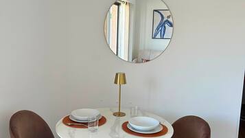 Un coin repas comprenant une table ronde, deux chaises, un miroir et un appareil de climatisation installé au-dessus.