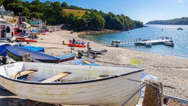 Una playa con barcos, un muelle y un edificio con balcón.