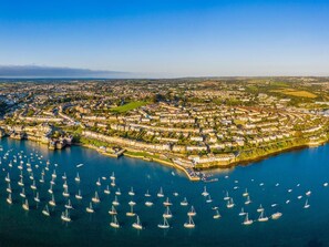 An aerial view of a coastal town with a marina filled with sailboats, surrounded by residential buildings and a clear sky. - 1 Bed in Falmouth (oc-85594) (Brill)