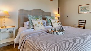 A neatly made bed with patterned pillows, a bedside table with a lamp, and a tray with mugs and biscuits. - 1 Bed in Derby (oc-76518) (Hilton)