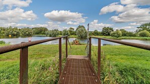 A metal bridge with a grid floor leading to a body of water, surrounded by greenery and trees. - 1 Bed in Derby (oc-76518) (Hilton)