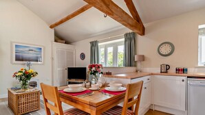 A cozy kitchen with wooden chairs, a dining table, a TV, and a clock on the wall. - 1 Bed in Derby (oc-76518) (Hilton)