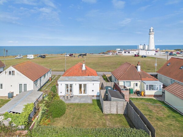 A coastal village with houses, a lighthouse, and a grassy area. - 2 Bed in Flamborough (oc-g0115) (Flamborough)