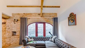 Ein gemütliches Wohnzimmer mit Steinwand, großem Fenster, einer Ledersofa und einem Holztisch.