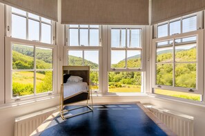A room with a bed, large windows, and a view of a green landscape. - 7 Bed in Machynlleth (oc-77466) (Glantwymyn)
