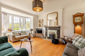 A living room with a fireplace, a television, and a large mirror.
