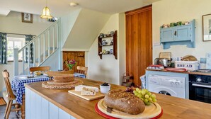 A kitchen with a wooden countertop, a loaf of bread, a cutting board, and a washing machine. - 1 Bed in Brecon (oc-bn129) (Yscir)