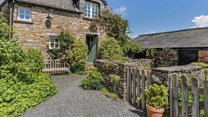 A stone house with a gravel driveway, wooden fence, and a green door. - 1 Bed in Brecon (oc-bn129) (Yscir)