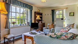 A cozy living room with a sofa, a table, a television, and a bookshelf. - 1 Bed in Brecon (oc-bn129) (Yscir)
