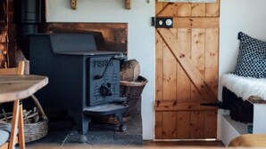 A cozy room with a black Fisher wood stove, a wooden door, and a map on the wall. - 1 Bed in Axminster (oc-82585) (Musbury)