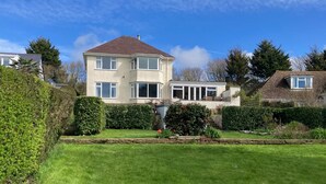 Ein zweistöckiges Haus mit Garten vor der Fassade.