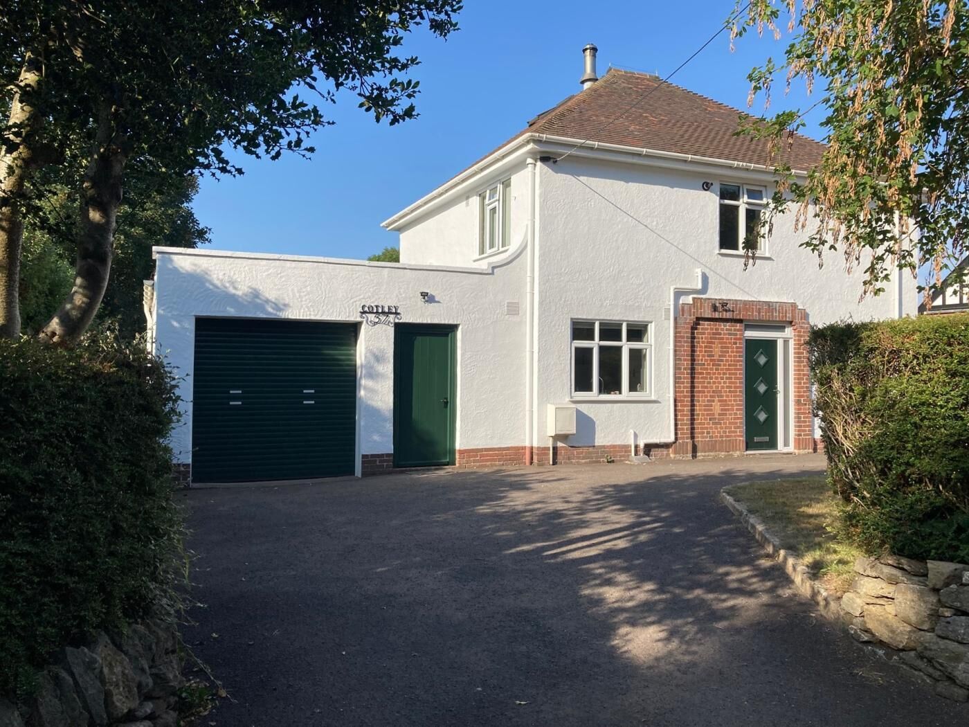 Een twee verdiepingen tellend huis met garage, een bakstenen ingang en heldere lucht.