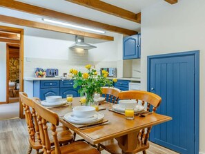 A dining area with a wooden table set for breakfast, blue cabinets, and a blue door. - 2 Bed in St. Austell (oc-82609) (Pentewan Valley)