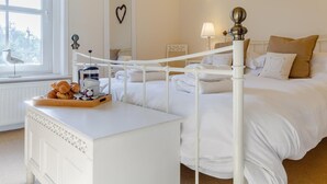A hotel room with a white bed, a bedside table with a tray of croissants, a window with a view, and a wall-mounted heart decoration. - 2 Bed in Holt (oc-ncc11) (Holt)