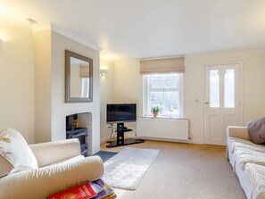 A living room with a sofa, a television, a radiator, and a window with a view. - 2 Bed in Holt (oc-ncc11) (Holt)