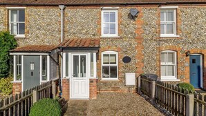 A two-story stone house with a front garden, a wooden fence, and a blue door. - 2 Bed in Holt (oc-ncc11) (Holt)