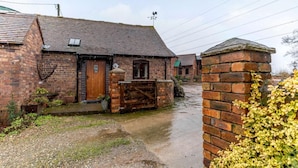 A brick building with a wooden door, a small window, and a metal gate. - 1 Bed in Leighton (oc-80726) (Leighton)