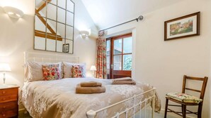 A bedroom with a bed, a chair, a nightstand, a window with curtains, and a picture on the wall. - 1 Bed in Leighton (oc-80726) (Leighton)
