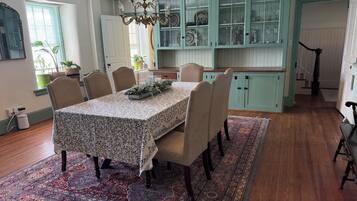 A dining area with a table set for four, surrounded by chairs, a patterned rug, and a chandelier.