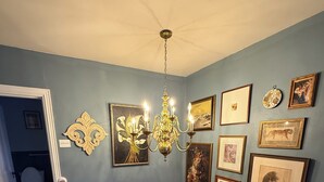 Un escalier avec une rampe en bois, un lustre et des œuvres d’art encadrées accrochées aux murs.