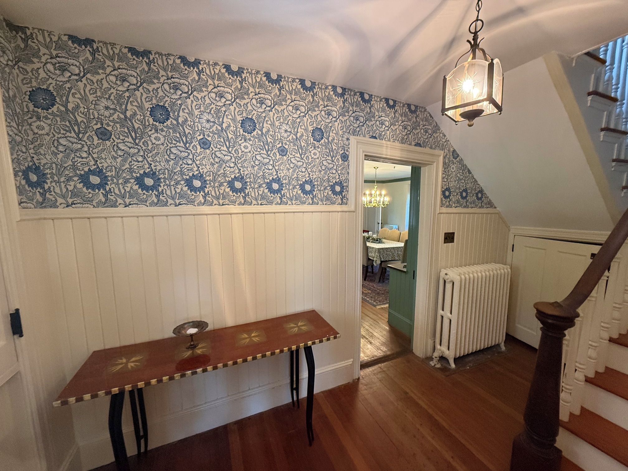 A room with a wooden bench, a radiator, and a staircase.