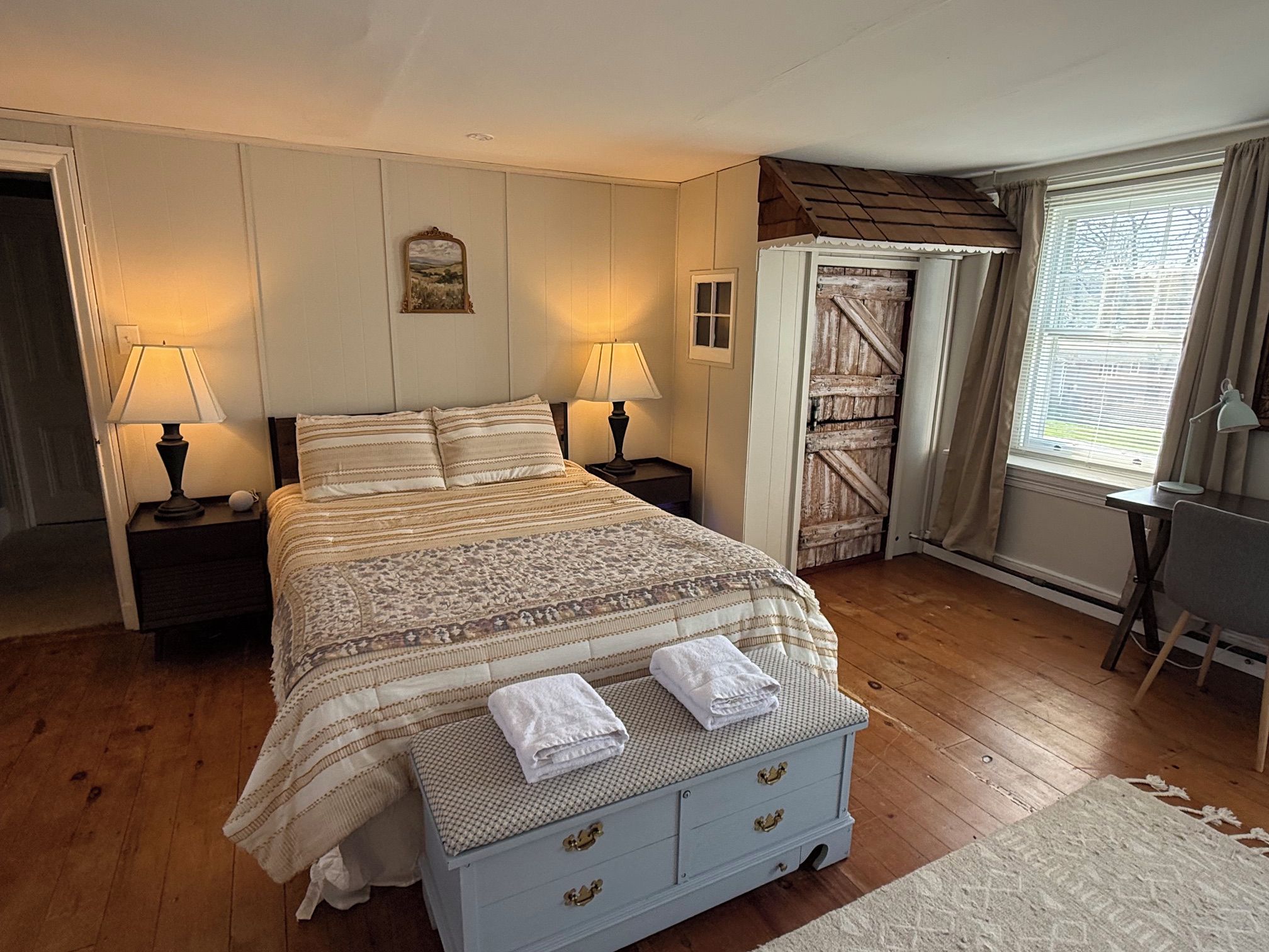 Un dormitorio con cama, dos lámparas de noche, mesita de noche, cómoda y ventana con cortinas.