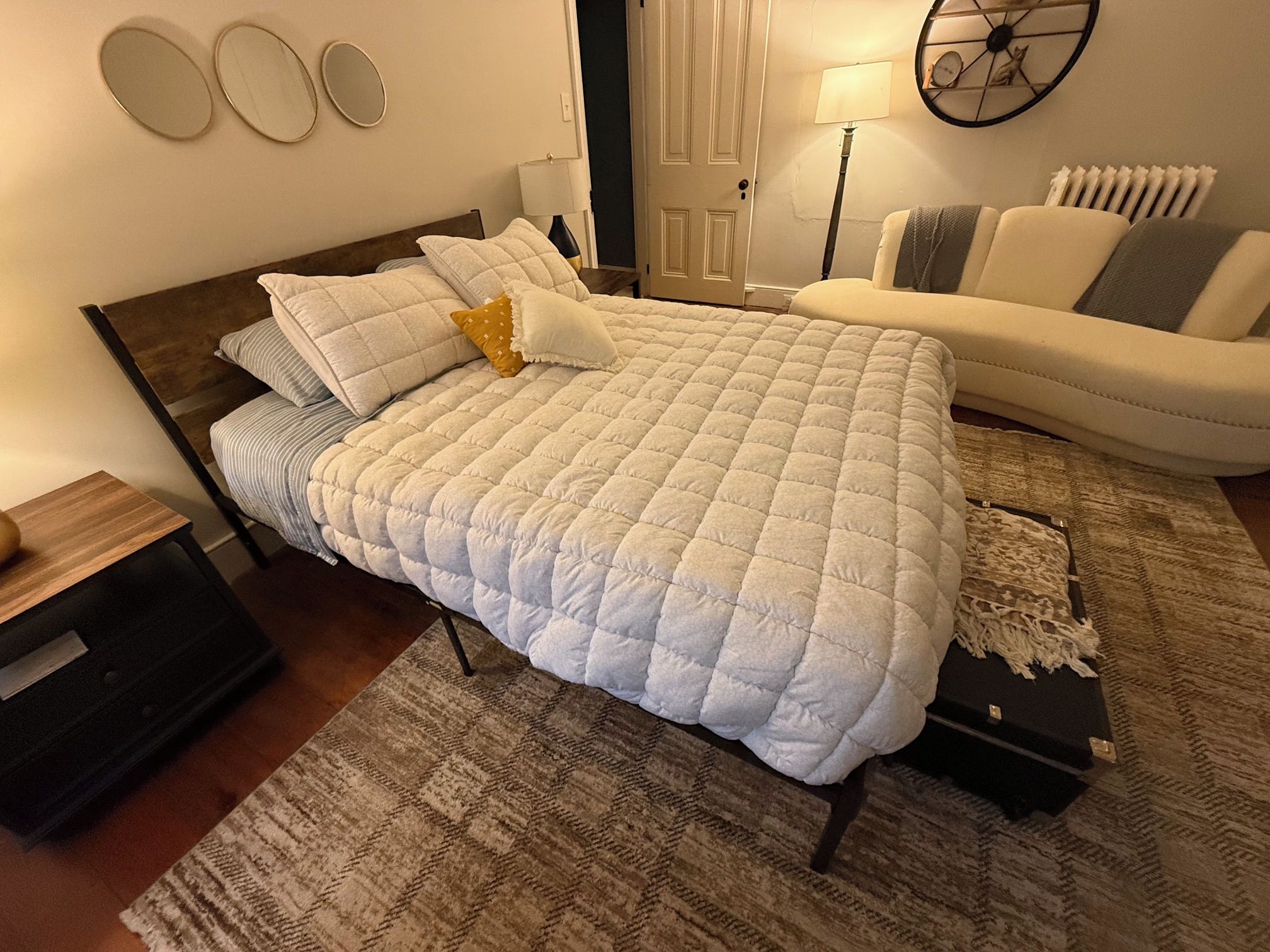 A bedroom with a bed, bedside tables, a dresser, a lamp, a clock, and a radiator.