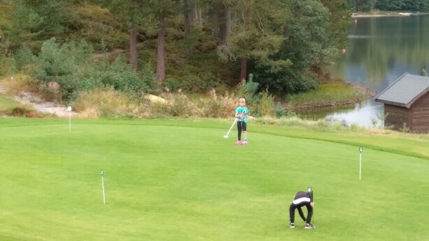 A golf course with a water body in the background and a wooden structure on the right. - Great location! (Telemark)