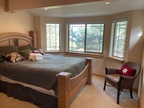 A bedroom with a bed, a chair, and three windows. - Large home in the Tahoe Keys! (South Lake Tahoe)